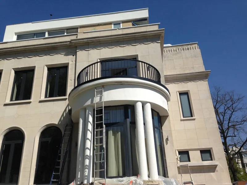 Façade en pierre naturelle après les travaux, bow-window arrondi sur colonnes, balcon courbe et nouvel étage en retrait.