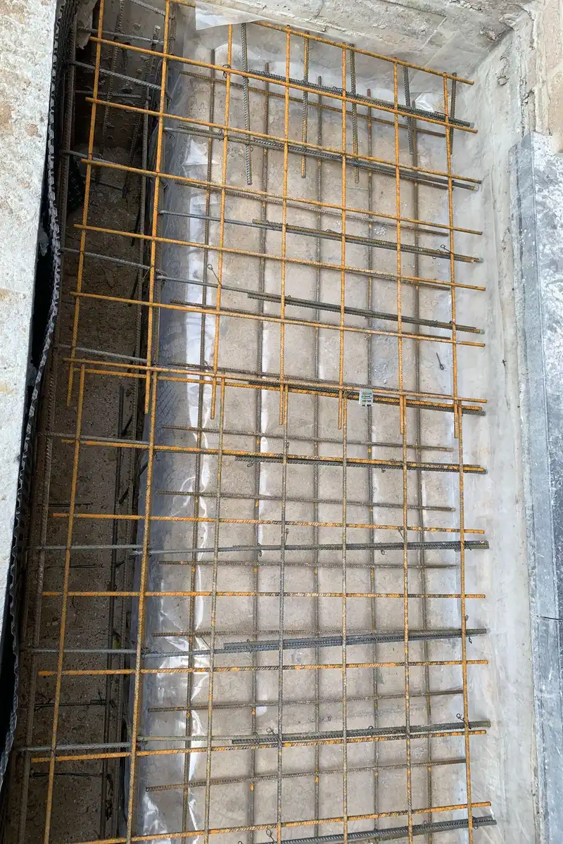 Treillis de ferraillage sur film de chantier, avec le long du bord une saignée armée dans son coffrage.