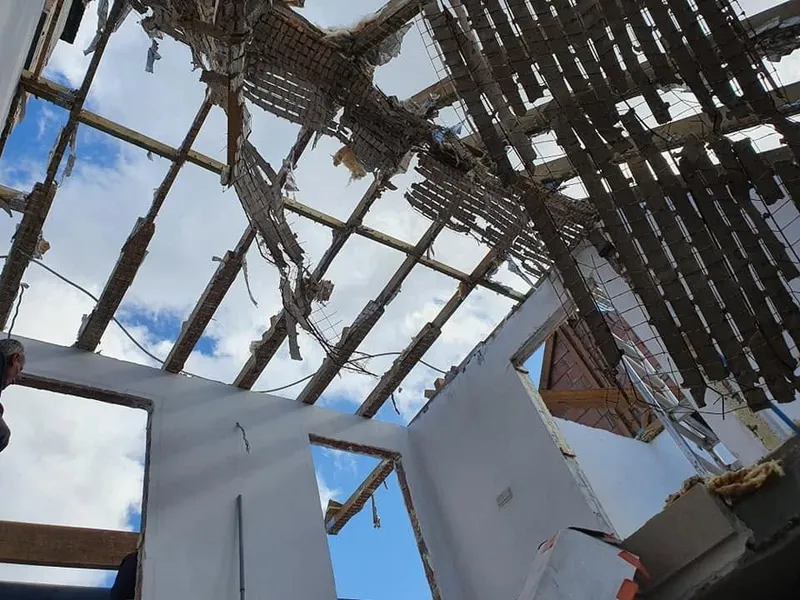 Vue vers le haut depuis l’intérieur : le voligeage est déposé, le ciel apparaît entre les fermes et les nouvelles cloisons sont en place.